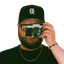 A self-portrait photograph of the author holding an SLR camera viewfinder to his eye, obsuring this face.