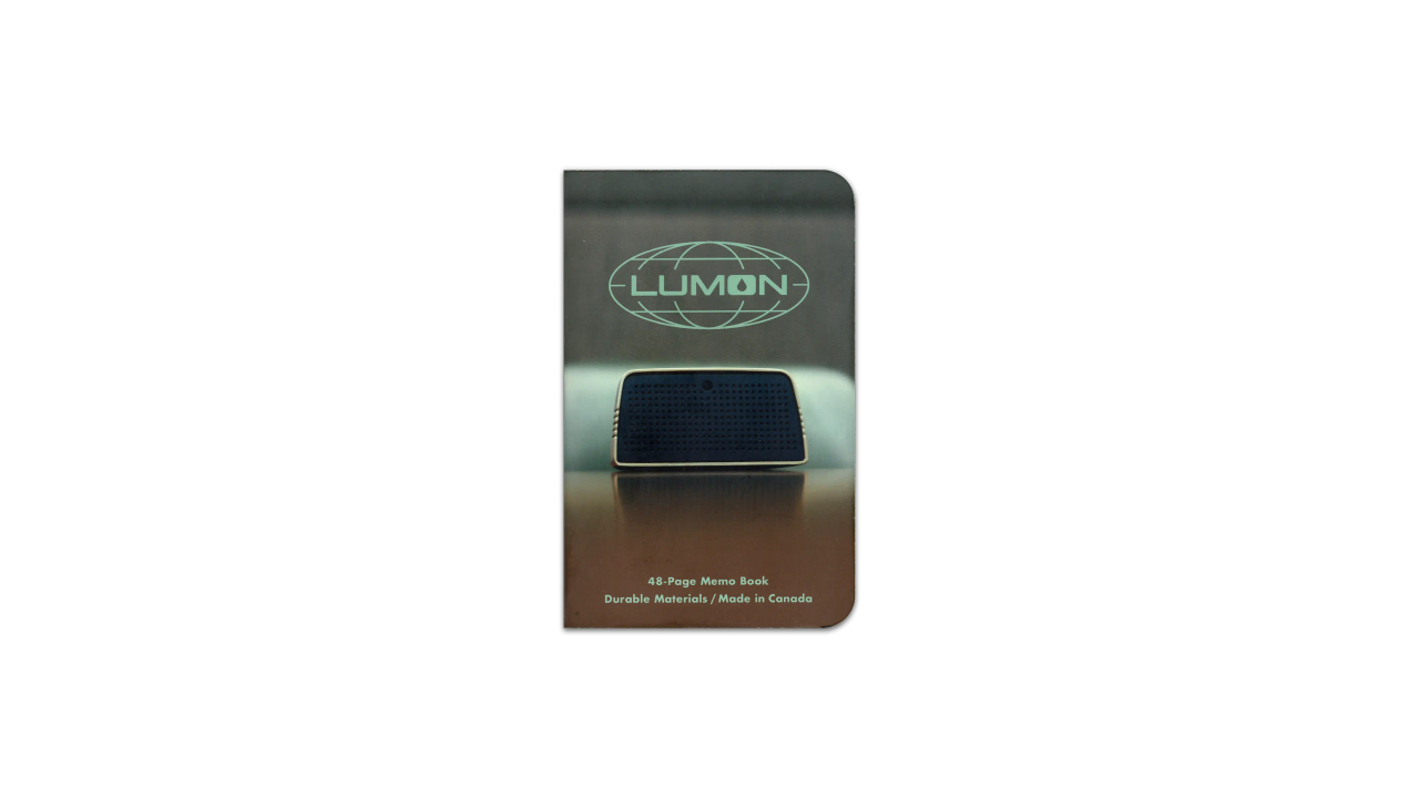 A digital scan of the cover of the journal I used during April, 2025. It is a custom MIKIE NOTES ‘Lumon Industries’ edition, featuring an image of a conference speaker on a desk, from a episode of Severance, Season 1.